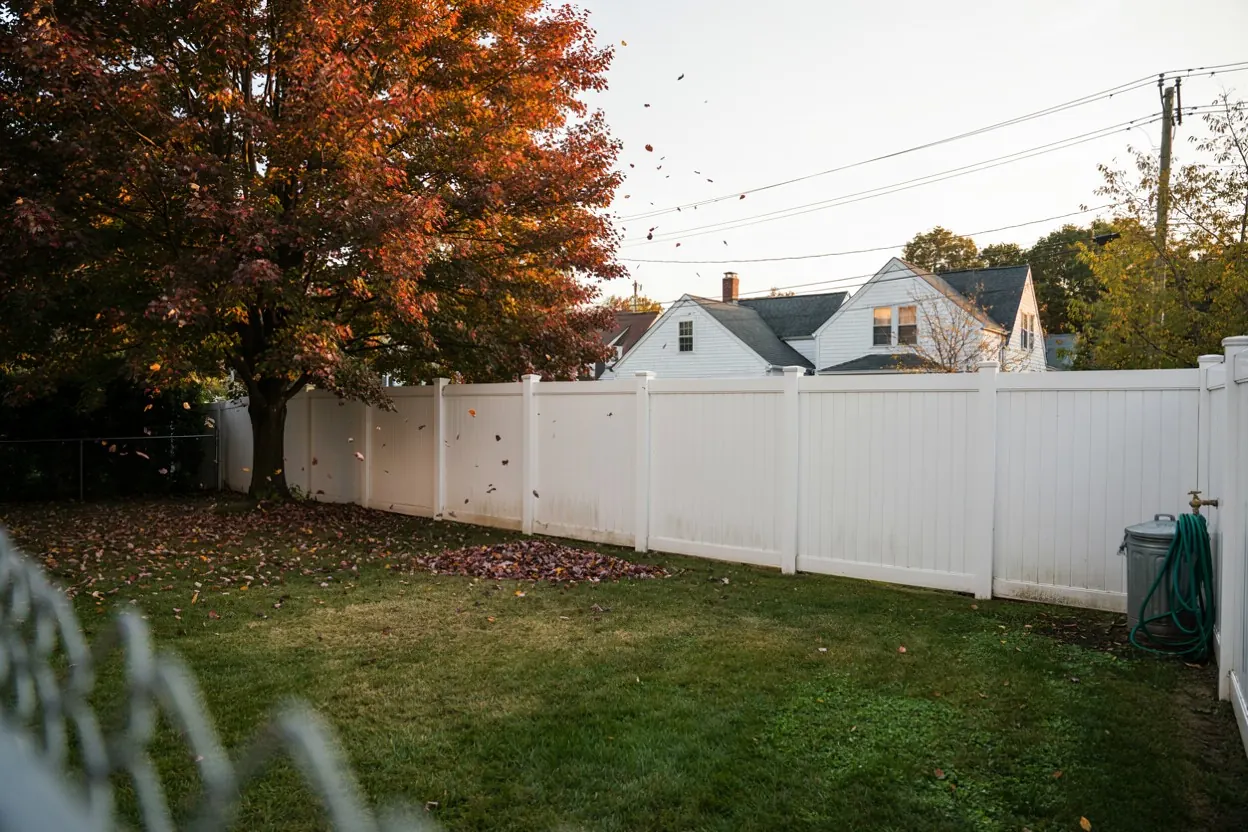 Vinyl-fenced backyard in a dense North Jersey suburb with oaks in autumn color