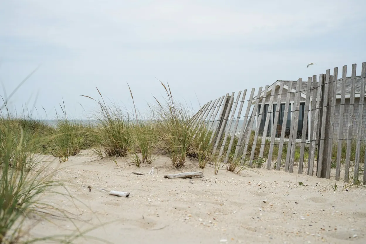 Weathered cedar fence and dune grass behind a Jersey Shore bungalow