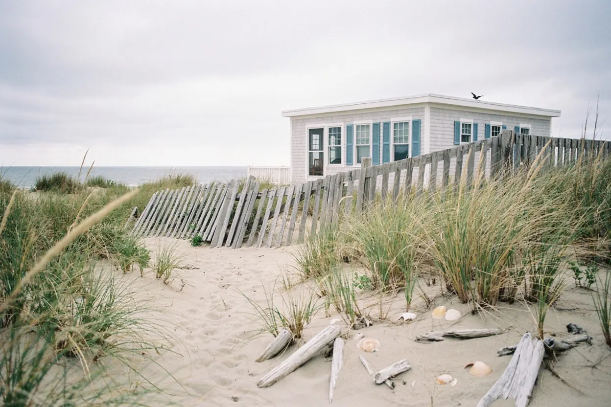 Weathered cedar fence and dune grass behind a Jersey Shore bungalow
